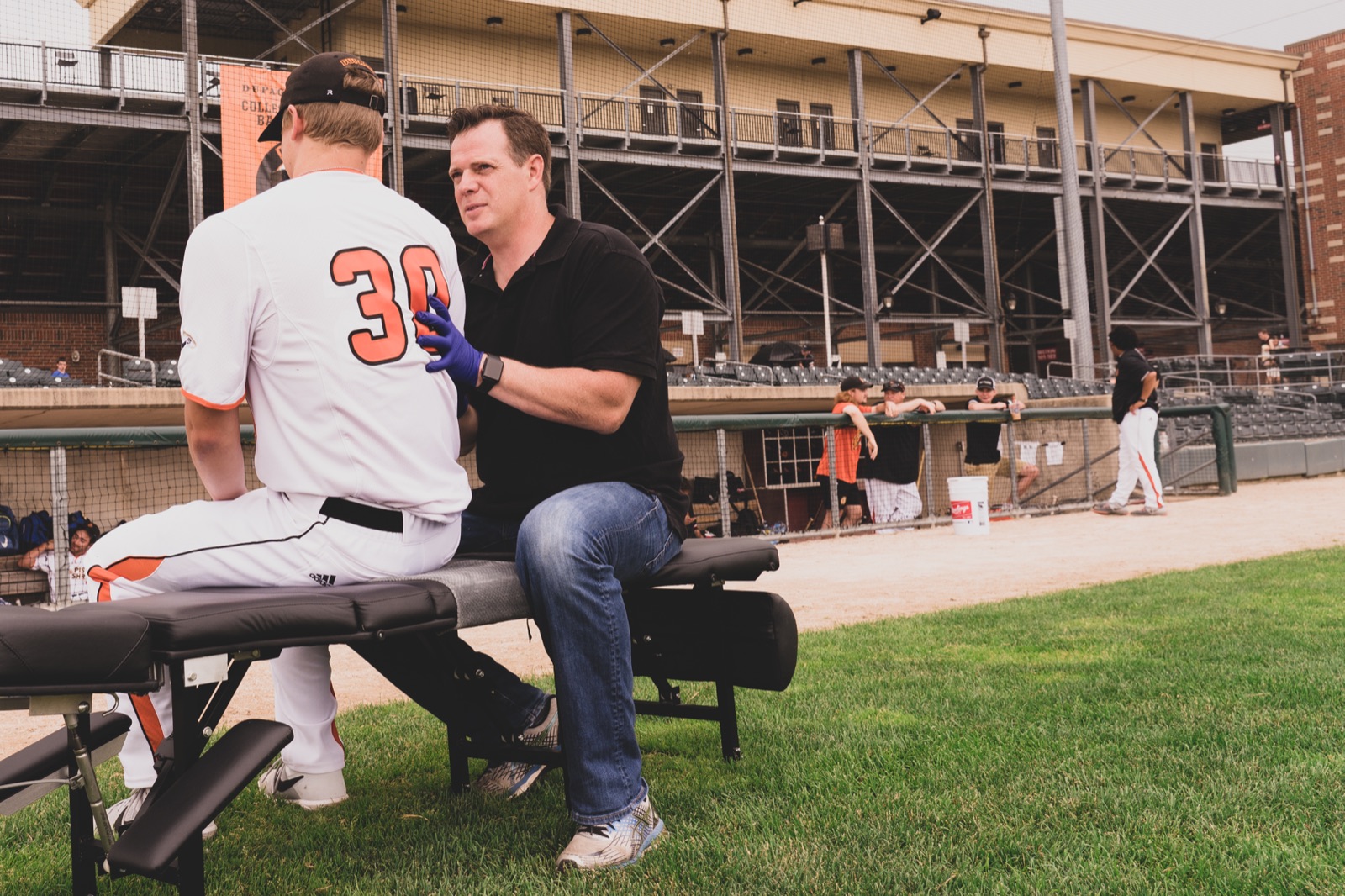 Dr. Justin Hunter talking with a seated athlete at Pure Health and Wellness in Naperville