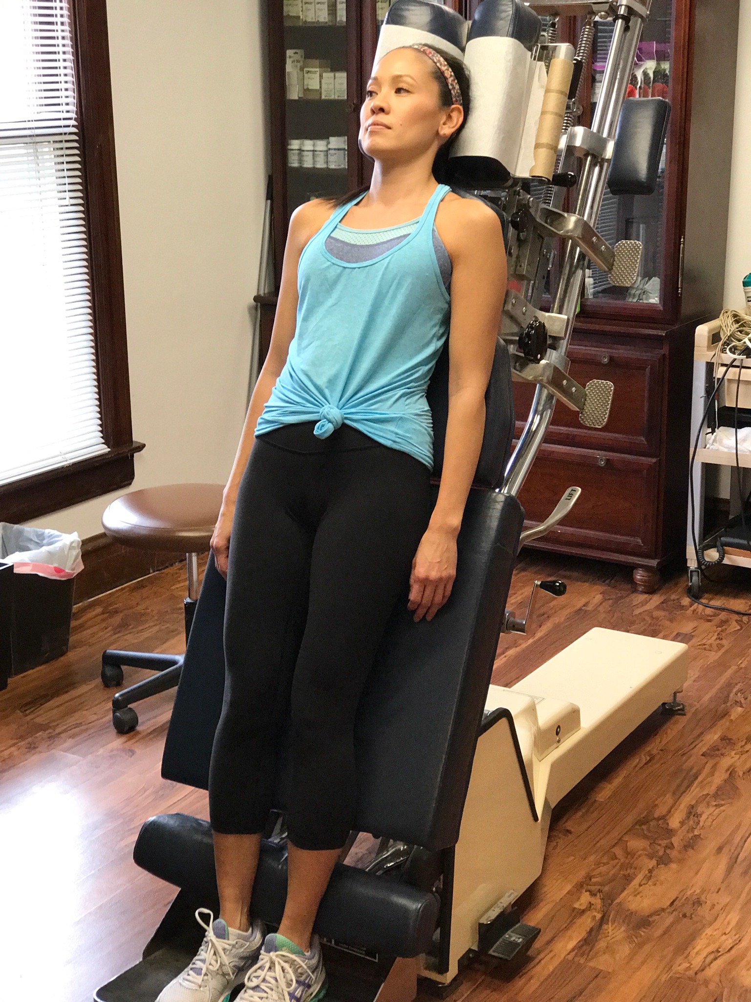 A patient standing against an upright treatment table before decompression work
